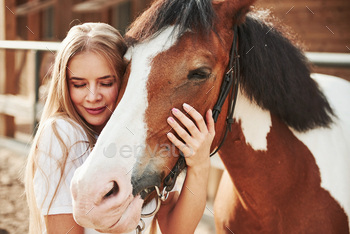 Embracing her horse. Happy woman on the ranch at daytime / Photodune