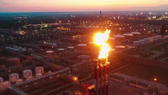 Sunset View of the Oil Refinery with Pipes Releasing Fire