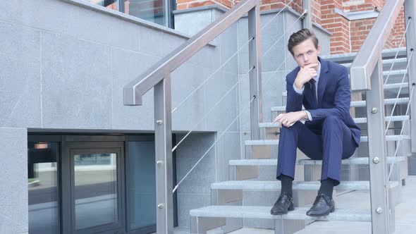 Pensive Thinking Young Businessman Sitting on Stairs Outside Office