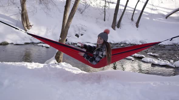 Woman sitting in hammock during winter calling dog over