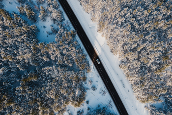 Aerial view of a car driving trough forest highway in winter / Photodune