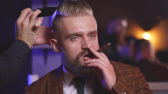 Hairstylist Does Hair Styling Hair To Businessman Smoking in Salon