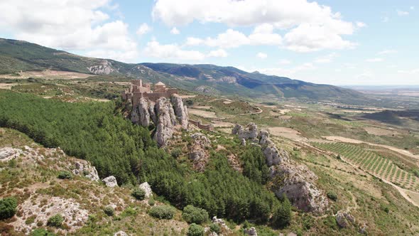 Beautiful castle on top of the big gray rocks among the green coniferous trees called Castillo de Lo