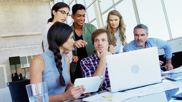 Business executives discussing over laptop