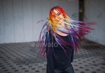Unusual elegant girl in a black simple dress with bright makeup and multi-colored braids posing / Photodune