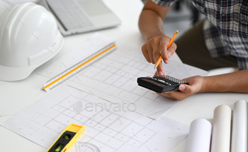cost of house plans, house plans, safety helmet and office equipment placed on the desk.