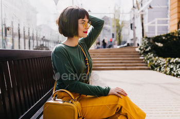 Graceful short-haired girl in sunglasses relaxing outdoor. Adorable woman in green sweater posing o / Photodune