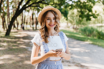 Romantic girl wears hat and white t-shirt smiling on nature background. Adorable fair-haired woman / Photodune