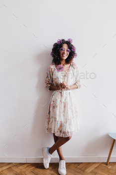 Full-length portrait of pleasant african girl in dress and white sneakers. Indoor photo of laughing / Photodune