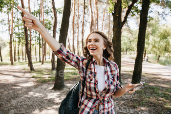 Stunning girl in checkered shirt pointing finger at something interesting. Outdoor portrait of refi / Photodune