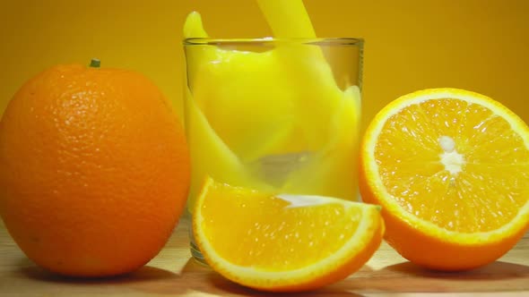 Fresh Delicious Orange Juice is Poured in a Glass Next to Large Ripe Oranges