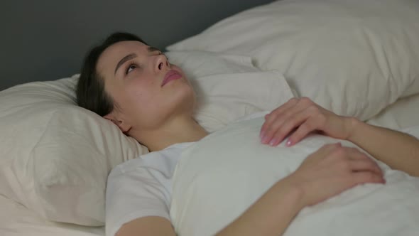 Pensive Young Woman Laying Awake in Bed 