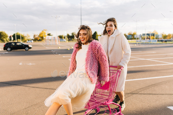 Stunning female friends posing at parking. Good-looking girls chilling in spring weekend / Photodune