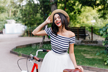 Blithesome caucasian girl in hat posing on nature background. Gorgeous brunette woman in skirt stan / Photodune
