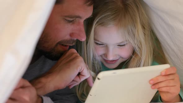 Happy father and daughter covered with blanket using tablet 4K 4k