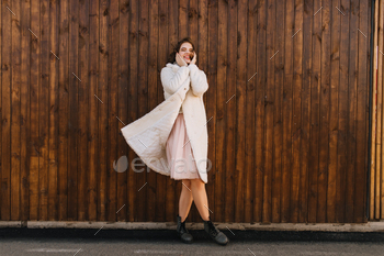Full-length shot of fashionable caucasian girl expressing sincere emotions in cold day. Outdoor pho / Photodune