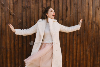 Glad female model in white coat laughing during photoshoot. Photo of ecstatic caucasian girl smilin / Photodune