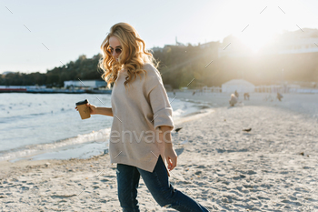 Good-humoured woman in sweater walking around beach in autumn morning. Outdoor shot of refined lady / Photodune