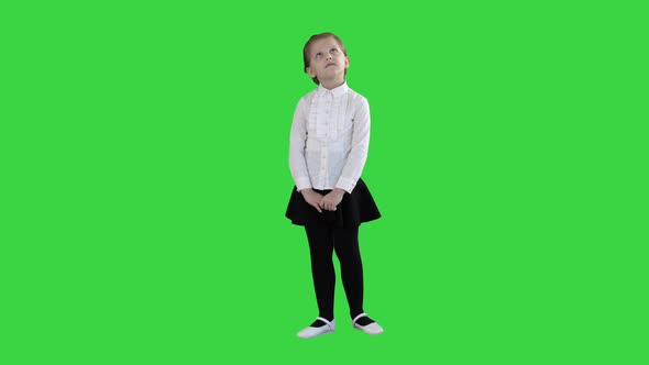 Cute Preschool Girl Standing Being Shy Looking Around and Thinking on a Green Screen, Chroma Key