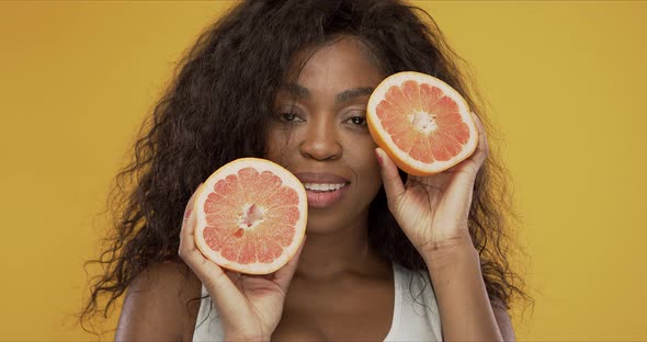 Cheerful Black Lady Showing Halves of Grapefruit