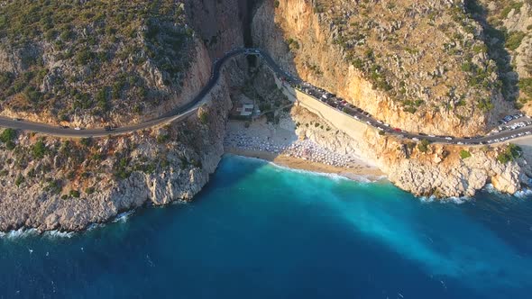 People Swim on Light Blue Sea in the White Sandy Beach Near the Rocky Mountainside