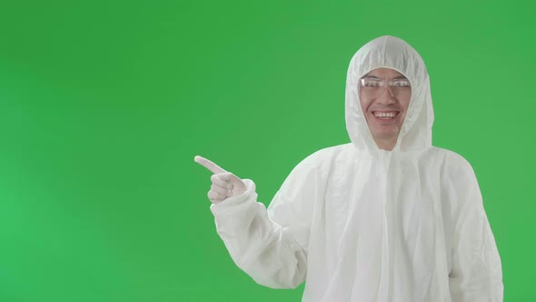 Asian Man Wearing Protective Uniform Ppe And Pointing To The Side In The Green Screen Studio