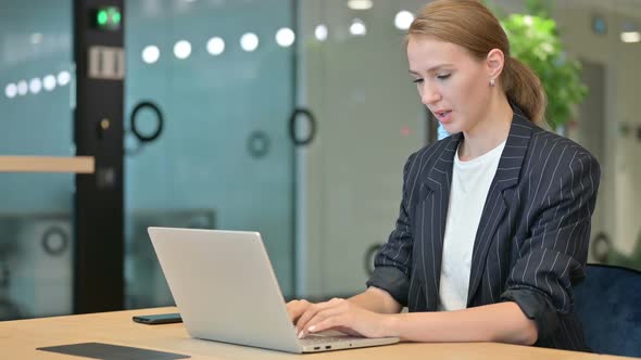 Sick Young Businesswoman with Laptop Coughing in Office