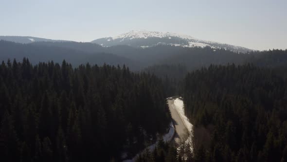 Aerial view of snowy mountain forest with a road