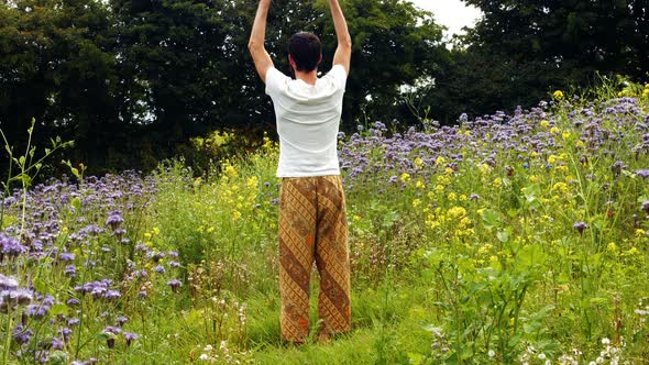 Rear view of man performing yoga on a field