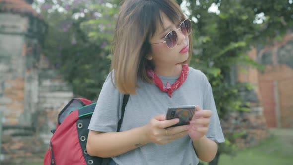 Asian woman using smartphone for direction and looking on location map while spending holiday