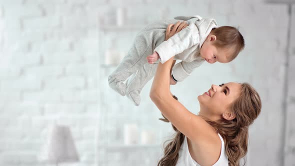 Attractive Mother Admiring Little Baby Rising Up Over Head Having Fun and Positive Emotion