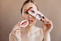 Woman without makeup looks into camera and holds photo of womens lips and eyes - PhotoDune Item for Sale