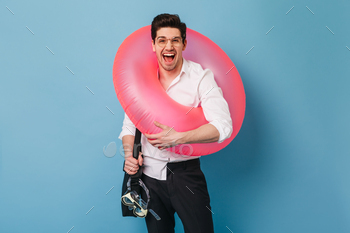 y in glasses posing with pink rubber ring and swimming mask on blue background
