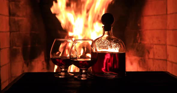 Two Glasses of Cognac and a Bottle Near the Fireplace