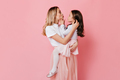Curly mom and daughter make faces on pink background. Portrait of woman and girl in same lush skirt - PhotoDune Item for Sale
