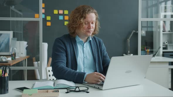 Tired Young Man Working with Laptop Typing Then Touching Eyes Suffering From Fatigue and Pain