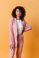 Front view of beautiful girl in pink suit. Curly mixed race woman in formal wear standing on yellow - PhotoDune Item for Sale