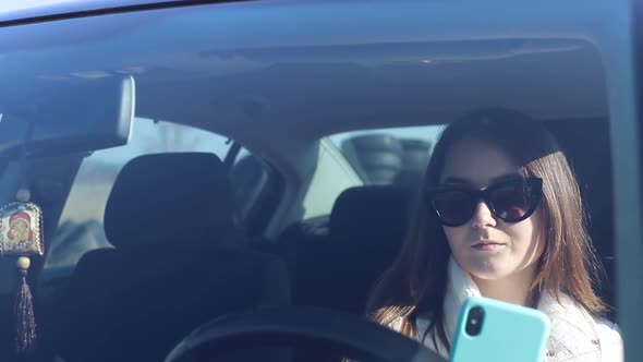 Girl Uses a Smartphone While Sitting in the Car