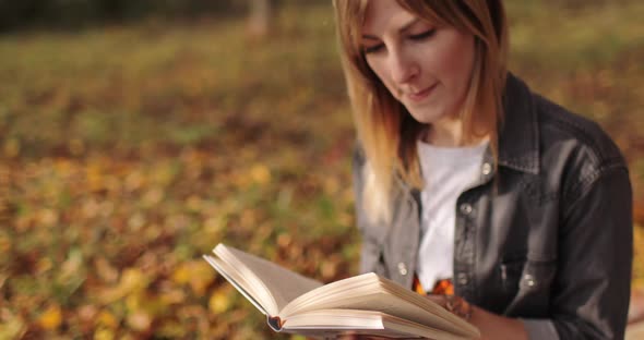 Thoughtful Woman Reading Book in Autumn Park