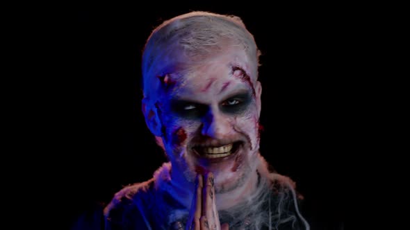 Scary Wounded Undead Man with Bloody Scars Face Making Faces Looks at Camera and Smiles Terribly