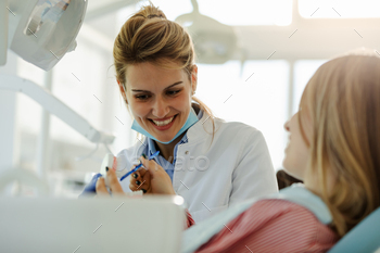 Female beautiful dentist is showing to patient how to brush teeth properly. / Photodune, Misc