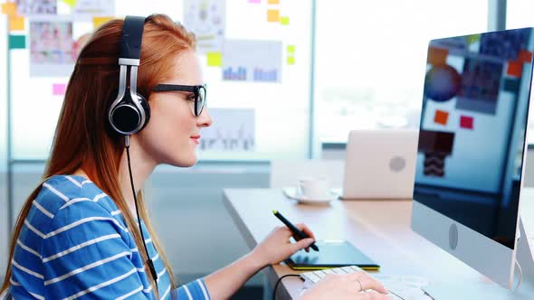 Female graphic designer working while listening music at desk