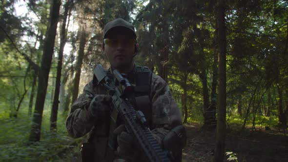 Closeup of Soldier with Rifle While Military Group Moving Behind