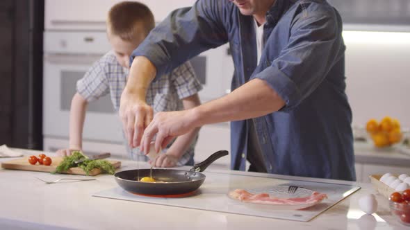 Father and Son Frying Eggs in Kitchen