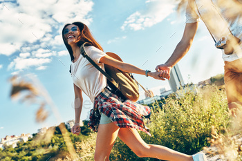 Romantic young couple of tourists in casual clothing holding hands and smiling / Photodune, Misc