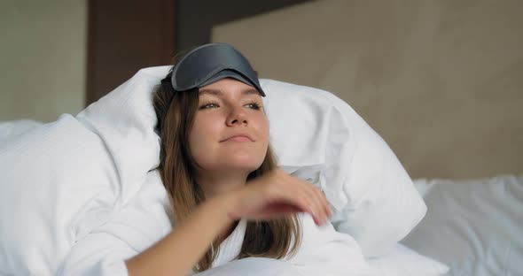 Pretty Lady Puts on Black Sleep Mask Lying Under Blanket