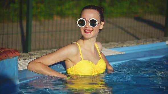 A Young Woman Who Enjoys Cool Water in the Pool Relaxes in the Summer Time