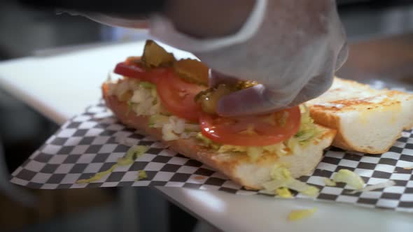 Sandwich prep, placing sliced dill pickles on crusty french bread, building a poboy, slow motion clo