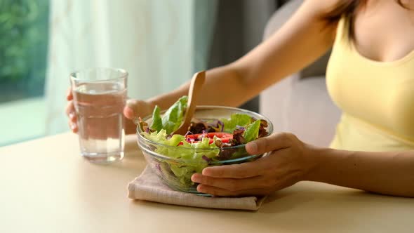 Young woman eating homemade healthy salad at home