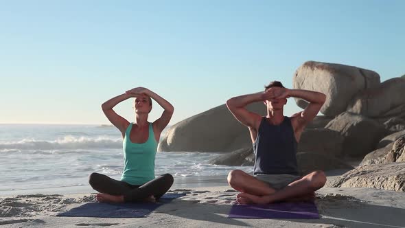 Young Couple Doing Yoga on Beach